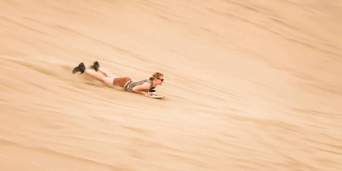 Sandboarding in Huacachina, adventure sport on Peruvian oasis dunes - Peru Bucket List