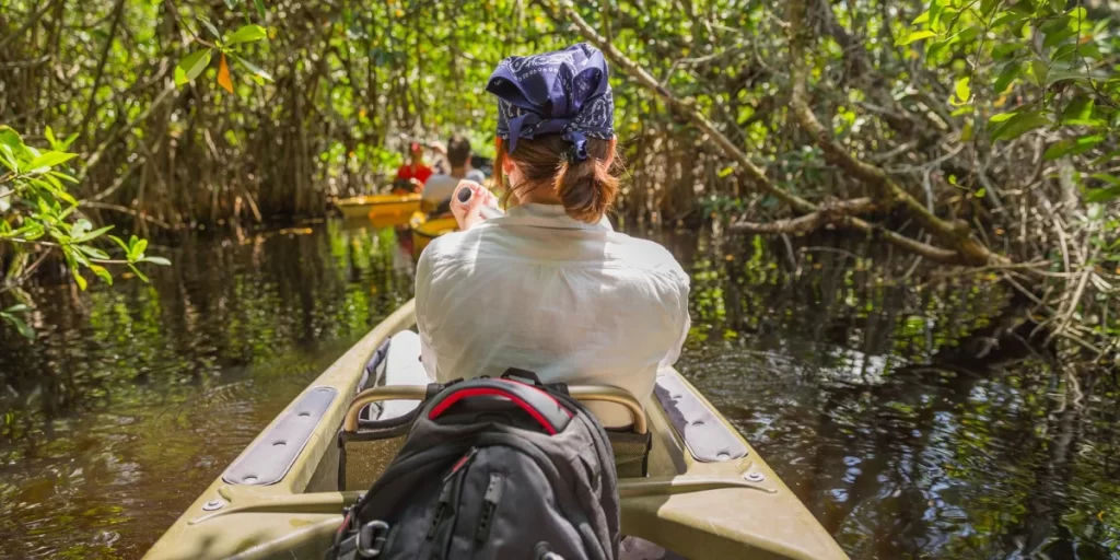 Traveler canoeing through the Peruvian Amazon surrounded by dense jungle - Peru Bucket List