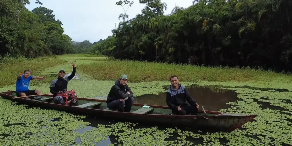 Travelers on an Amazon canoe tour safely touching the water from the boat, a recommended alternative to swimming