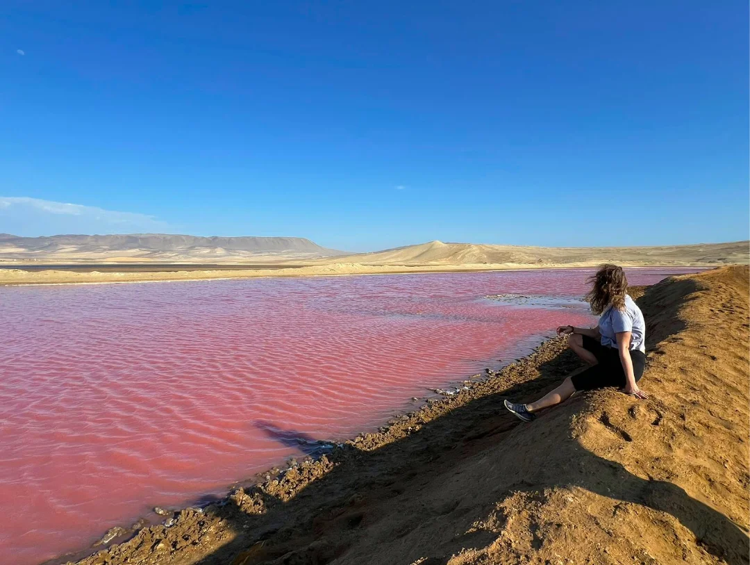 Traveler admiring the stunning pink lagoon during the Golden Shadow Trek inside Paracas National Reserve, Peru