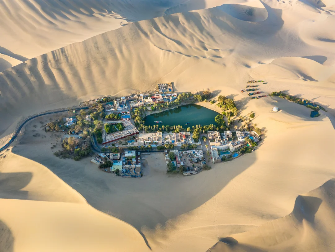 Aerial view of Huacachina Oasis surrounded by giant sand dunes in Ica Peru