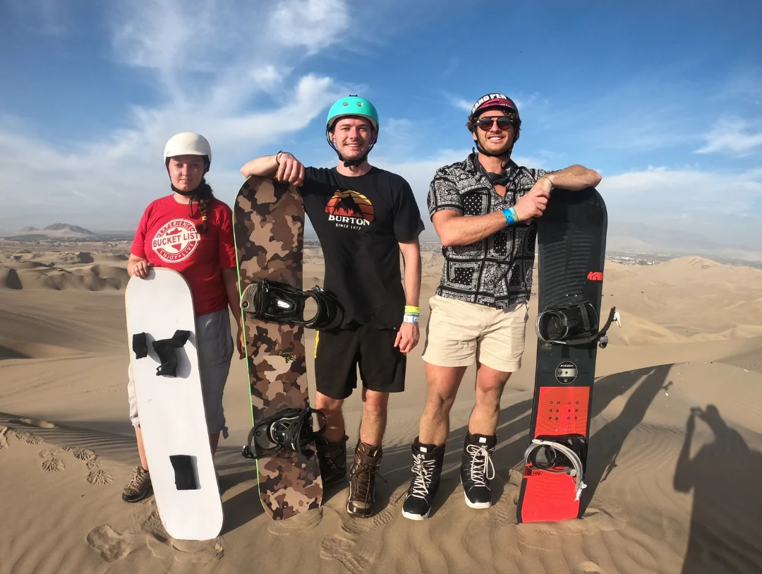 Travelers with professional sandboards during the Huacachina sandboarding experience on a 2 Days Paracas & Huacachina Tour from Lima
