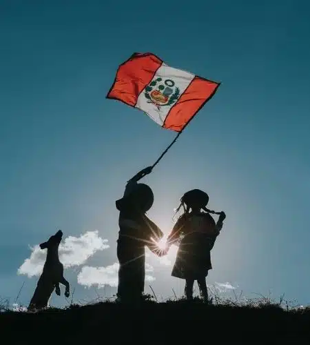 Peruvian flag held by travelers against the sky
