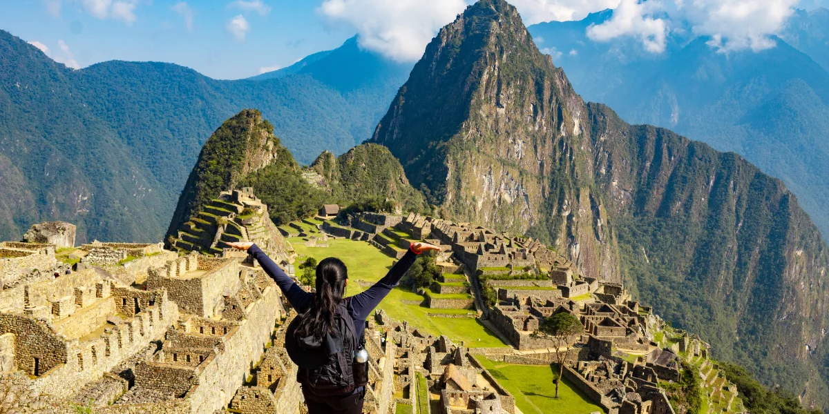 Machu Picchu in Peru on a clear sunny day with a traveler overlooking the Inca ruins