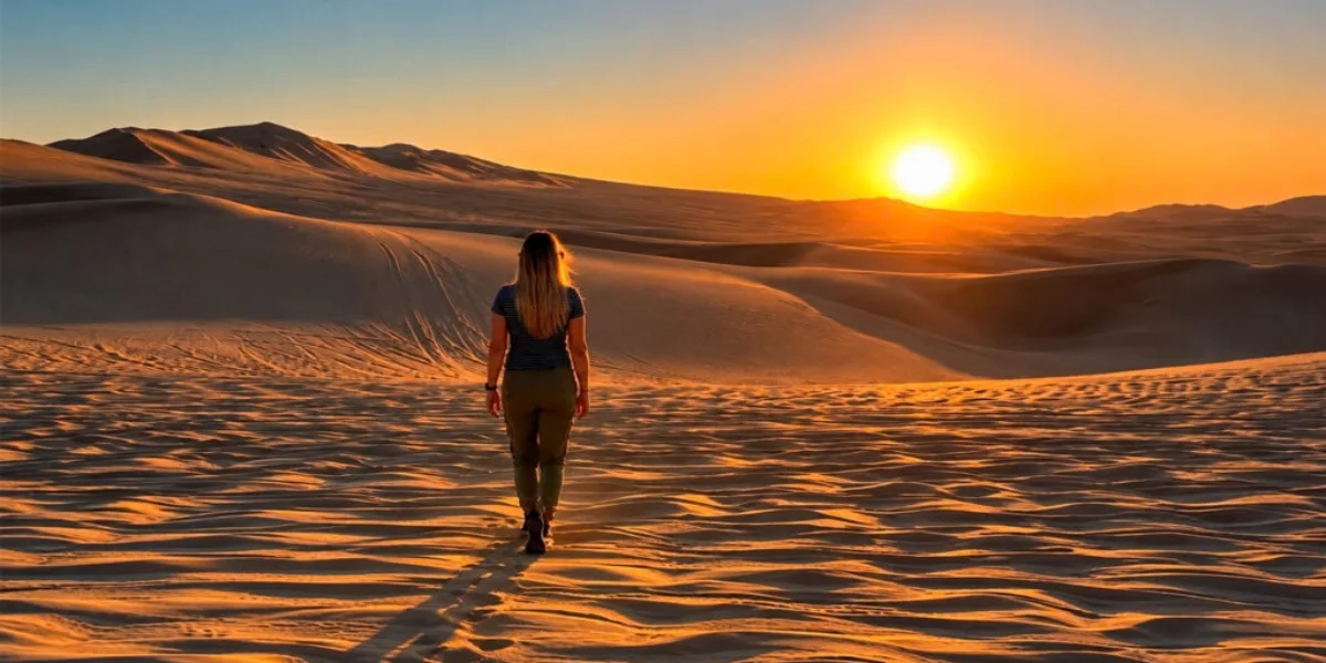 Traveler walking through the desert dunes of Nazca Peru at sunset